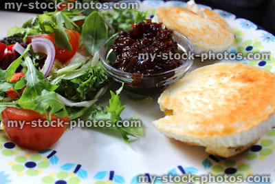 Stock image of English muffins with grilled goat's cheese, salad, onion marmalade relish