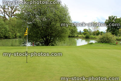 Stock image of putting green grass and flag at hole on golf course