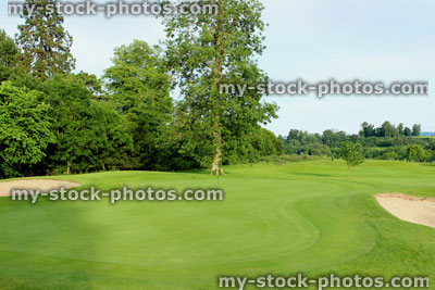 Stock image of putting green, fine grass, bunkers, flag, hole on golf course
