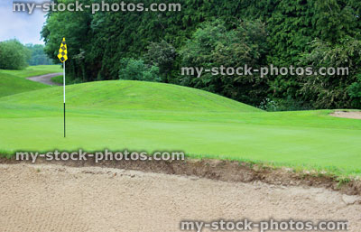 Stock image of putting green grass and flag at hole on golf course