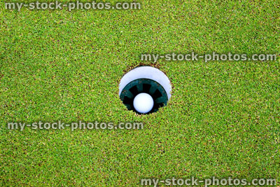 Stock image of golf ball in hole and flag, putting green, golf course