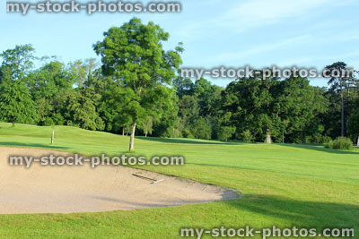 Stock image of golf course with sandy bunker trap, sand hazard, garden rake