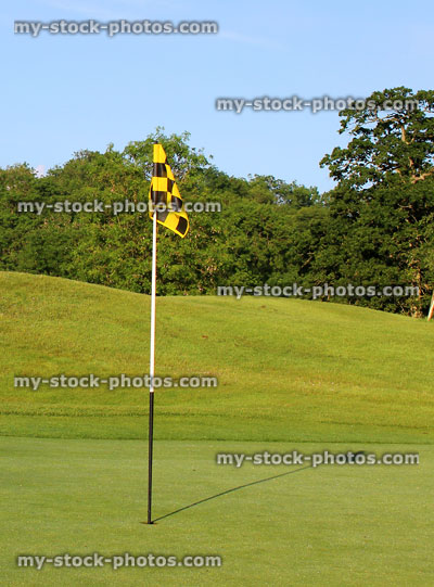 Stock image of golf course putting green, with flag and hole