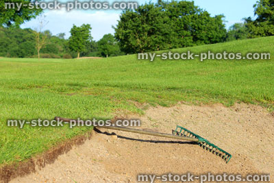 Stock image of golf course with sandy bunker trap, sand hazard, garden rake