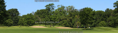 Stock image of golf course, bunkers, trees, blue sky, wide panorama