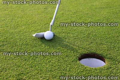 Stock image of golfer putting ball into hole at golf course