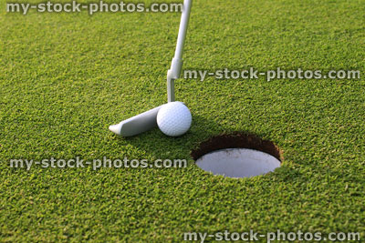 Stock image of golfer putting ball into hole at golf course, putting green