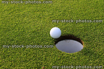 Stock image of ball by putting green hole on golf course