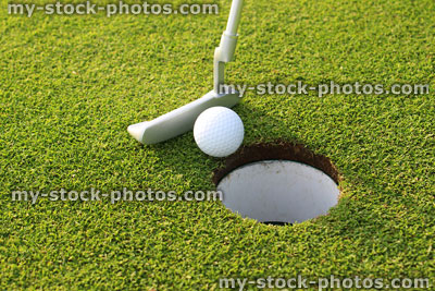 Stock image of golfer putting ball into hole at golf course
