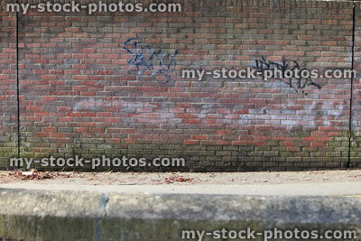 Stock image of pavement, road, dirty wall with red bricks / graffiti