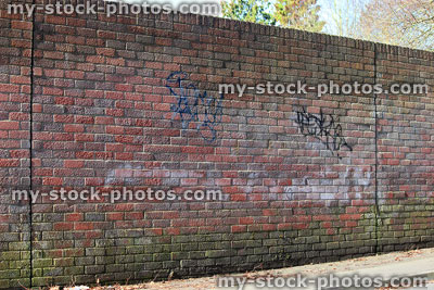 Stock image of dirty red brick wall with graffiti tags spray painted