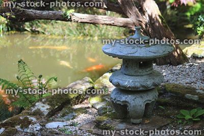 Stock image of granite Japanese lantern by koi pond (Maru Yukimi)