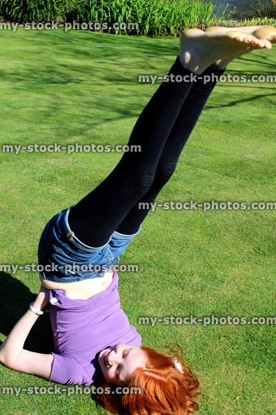 Stock image of red haired girl exercising and stretching on a manicured lawn
