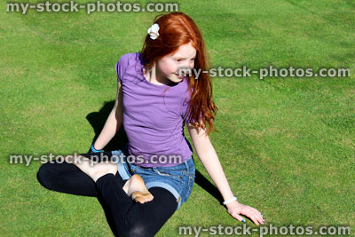 Stock image of red haired girl posing in lotus position on manicured lawn