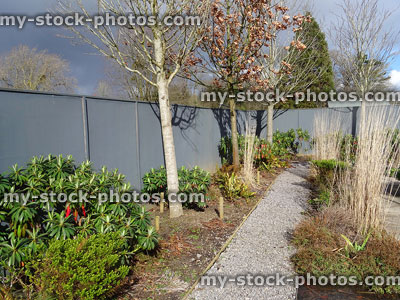 Stock image of garden pathway covered with grey gravel mulch, shrubs