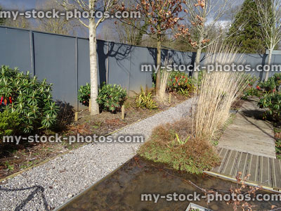 Stock image of garden with gravel and decking pathways, rectangular pond