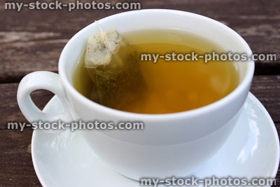 Stock image of cup of green tea, white cup, saucer, teabag