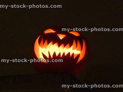 Stock image of carved pumpkin head, scary Halloween face, candle, illuminated glowing orange