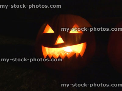 Stock image of carved pumpkin head, scary Halloween face, candle, illuminated glowing orange