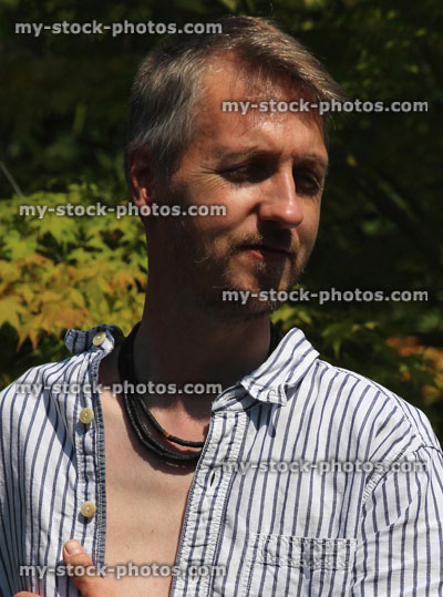 Stock image of man standing in sunny garden, enjoying strong sunshine