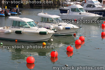 Stock image of red plastic floating mooring buoys with marina boats