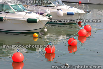Stock image of red mooring buoys floating by small yachts in marina