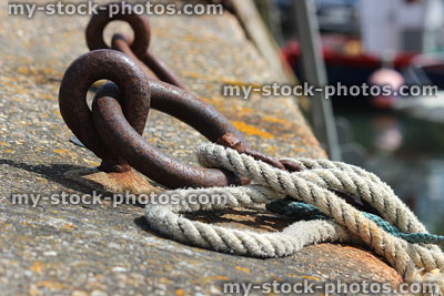 Stock image of rusty mooring rings on harbour wall, rope ties