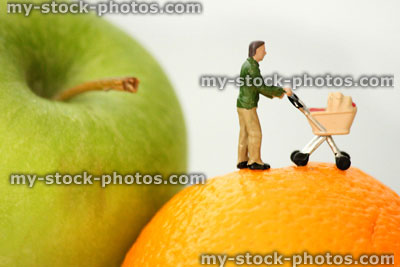 Stock image of healthy eating concept, mini people father and stroller on fruit