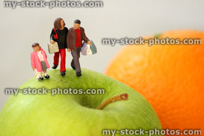 Stock image of healthy eating concept, with family of mini people on fruit 