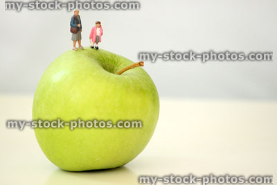 Stock image of healthy eating concept, with mini people walking on fruit 