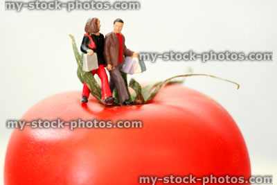 Stock image of healthy eating concept, with figurine couple walking on a tomato