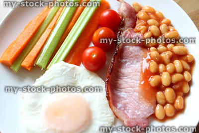 Stock image of low calorie, healthy fried breakfast, bacon, poached egg, raw vegetables, tomatoes, baked beans