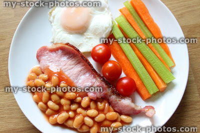 Stock image of low calorie, healthy fried breakfast, bacon, poached egg, carrots, celery, tomatoes, baked beans