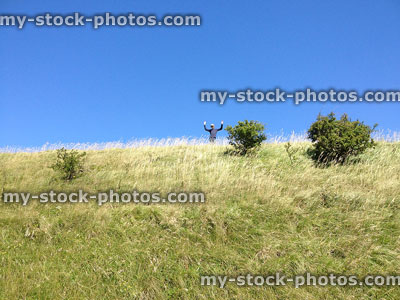 Stock image of young boy standing at top of grass hill