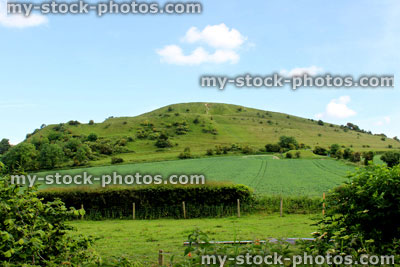 Stock image of steep hill in countryside, with fence, green fields