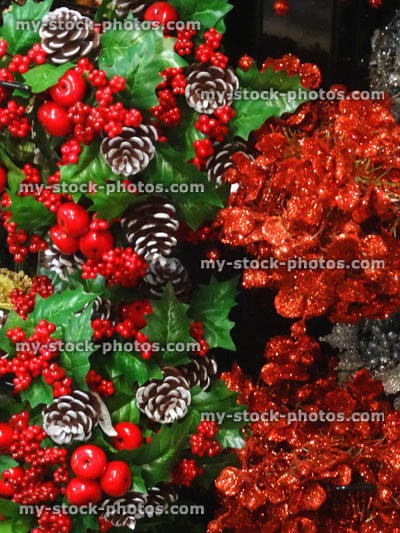 Stock image of artificial holly berries, pine cones, Christmas decorations, red plastic foliage / glitter leaves