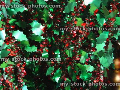 Stock image of coloured tinsel Christmas decorations, sparkling green holly leaves, red berries garland