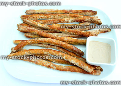 Stock image of plate of homemade breadsticks with hummus dip