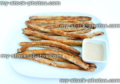 Stock image of plate of homemade breadsticks with hummus dip