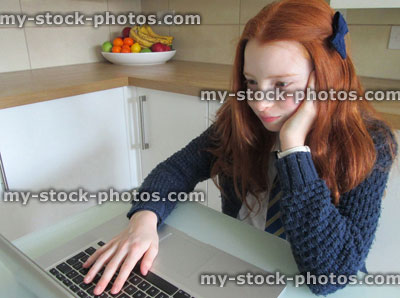Stock image of girl sat in front of laptop at kitchen table