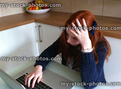 Stock image of school girl sat in front of laptop computer doing homework