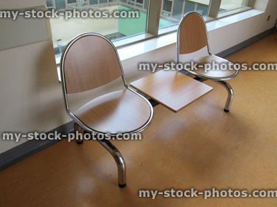 Stock image of chrome and wooden seats in a hospital corridor