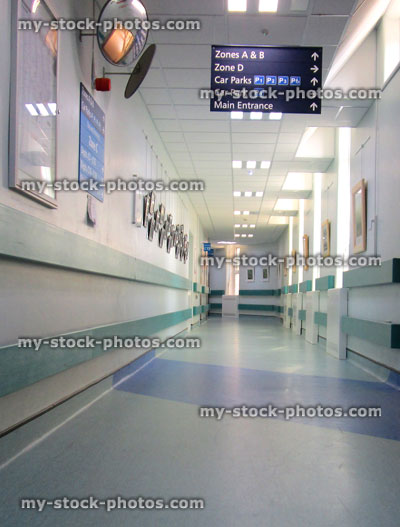Stock image of NHS hospital corridor with signs, signposts, blue vinyl floor