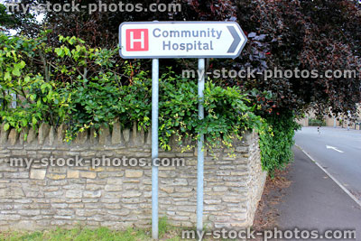 Stock image of white road sign / signpost pointing to Community Hospital