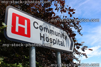 Stock image of hospital sign / white road sign / signpost pointing to Community Hospital