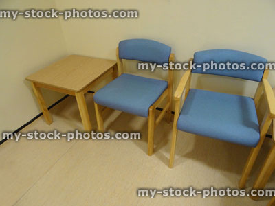 Stock image of cushioned blue and wooden seats in rows, hospital waiting room