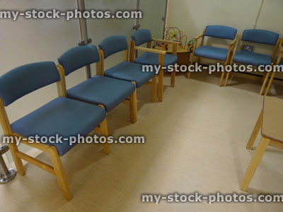 Stock image of cushioned blue and wooden seats in rows, hospital waiting room