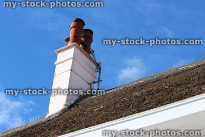 Stock image of terracotta chimney pots / white stack, thatched roof, pigeon spikes