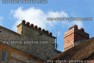 Stock image of contrasting stone and red brick chimneys, thatched roof