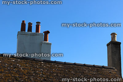 Stock image of white and stone chimneys, terracotta chimney pots, slate roof tiles